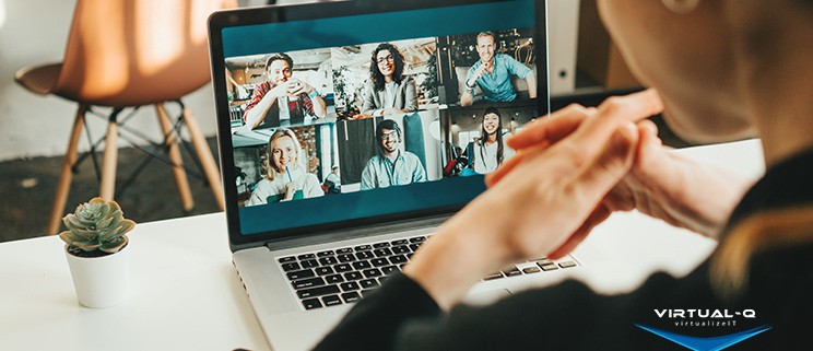 woman uses laptop to video conference with six coworkers