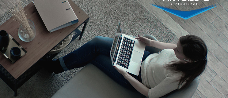 VirtualQ_August_LinkedIn_Article1 birds-eye view of woman sitting on couch holding a laptop