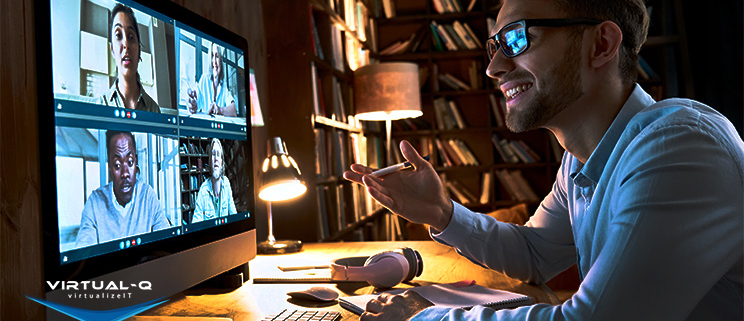 smiling man uses desktop computer to video conference with four coworkers