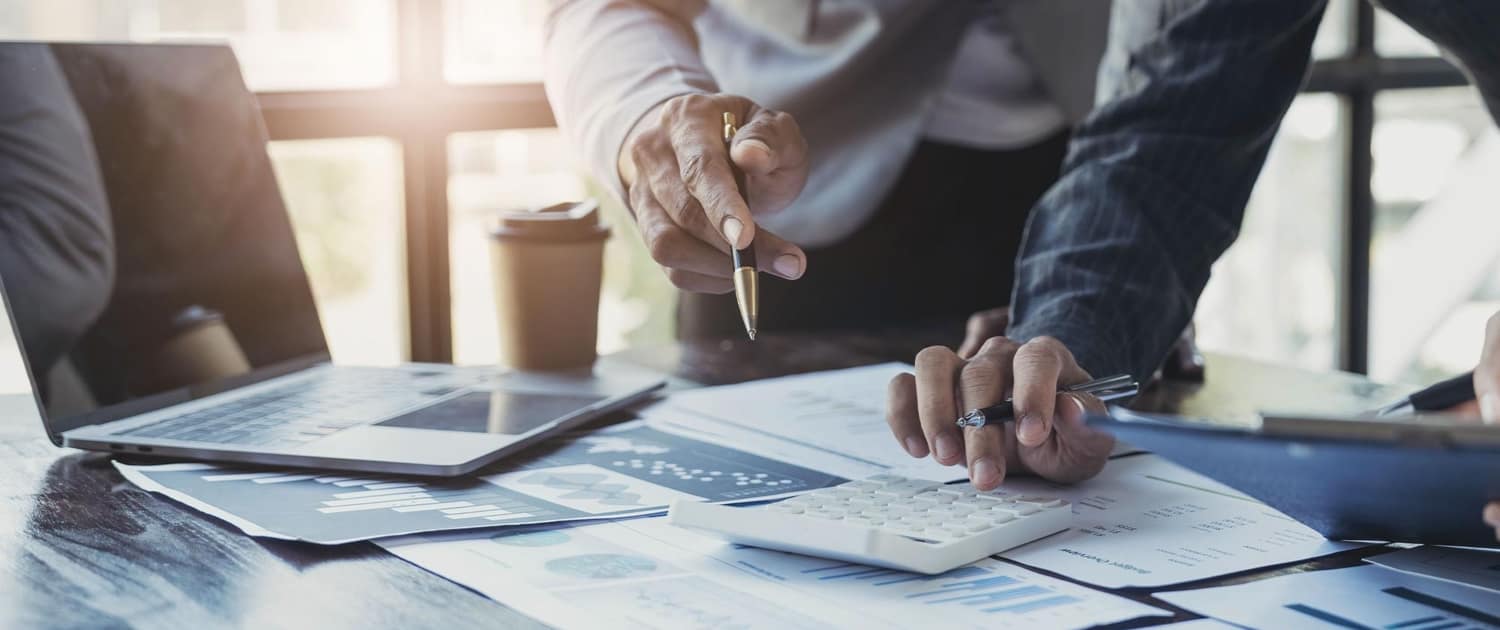 Image of business people reviewing paperwork next to a laptop Image of business people reviewing paperwork next to a laptop.