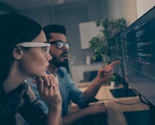 Two people looking at code on a computer